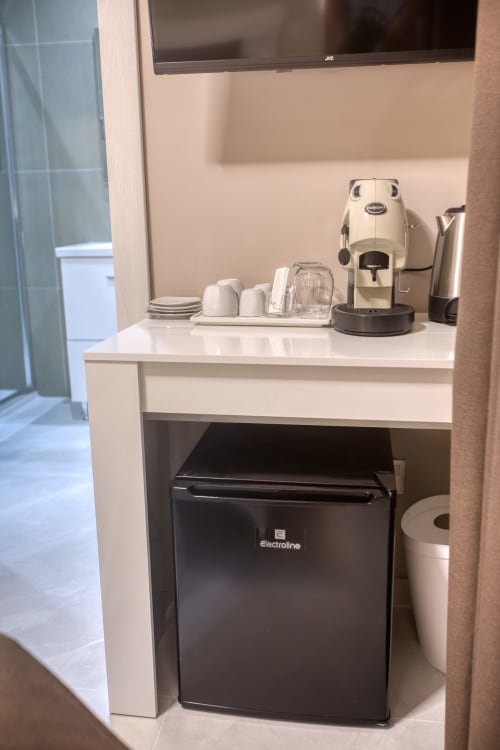 Angolo caffè in camera d'hotel con macchina Lavazza, frigobar, tazze e accessori presso Marea Sliema