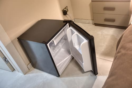 Frigorifero compatto con porta aperta nella camera da letto Marea Sliema, con ripiani vuoti e interno bianco