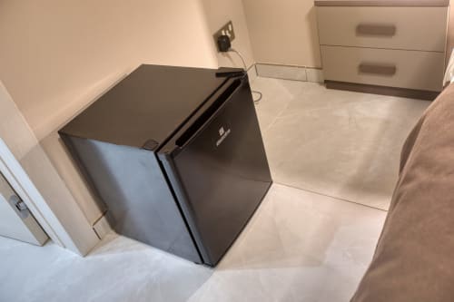 Mini frigorifero nero nella camera Marea Sliema Seaview con pavimento piastrellato e arredamento bianco