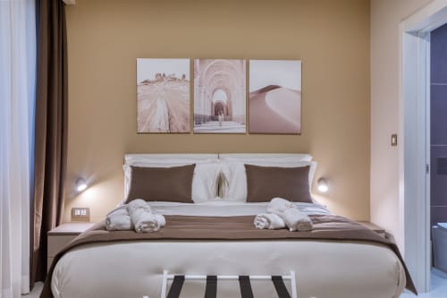 Camera elegante all'hotel Marea Sliema a Malta con tonalità neutre, opere d'arte a tema desertico, biancheria bianca e cuscini marrone