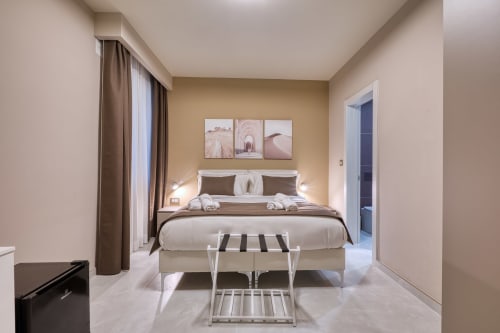 Camera elegante a Marea Sliema con letto matrimoniale, arredamento moderno, pareti beige e vista sulla corte interna