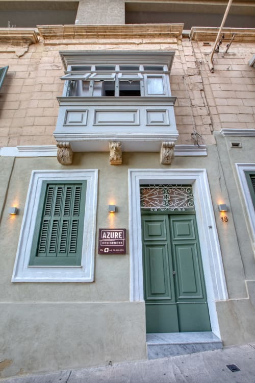 Ingresso di Azure Residences a Sliema, Malta con porte e persiane verdi, cornici bianche e corbellini decorativi