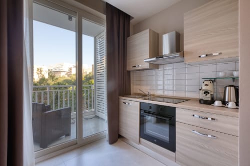 Cucina moderna con vista sul mare dell'appartamento Marea a Sliema, Malta, con mobili in legno chiaro e accesso al balcone