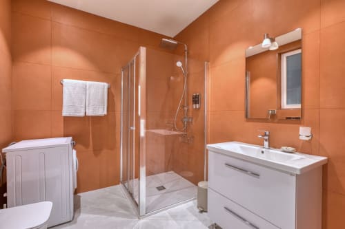 Bagno moderno a Marea Sliema con piastrelle arancioni, doccia walk-in, vanity bianco e finiture luminose a Sliema