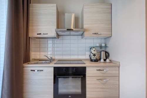 Angolo cottura moderno dell'appartamento Marea Sliema con vista mare: mobili in legno chiaro, rivestimento piastrelle bianche, forno nero