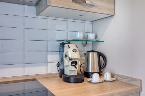 Moderna cucina angolare a Marea Sliema con caffettiera, bollitore, piastrelle bianche e mensola in vetro a Sliema