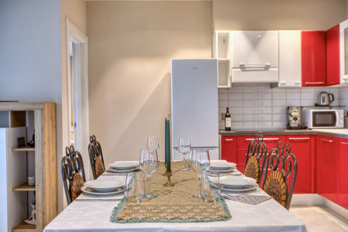 Elegante zona pranzo con tavolo apparecchiato nell'appartamento Marea di Sliema, con cucina rossa e balcone vista mare