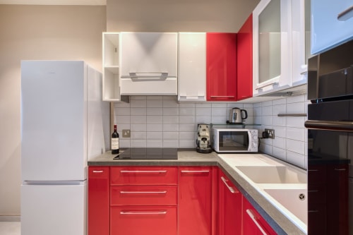 Cucina moderna rosso e bianca con elettrodomestici in acciaio inox nell'appartamento Marea Sliema, Malta