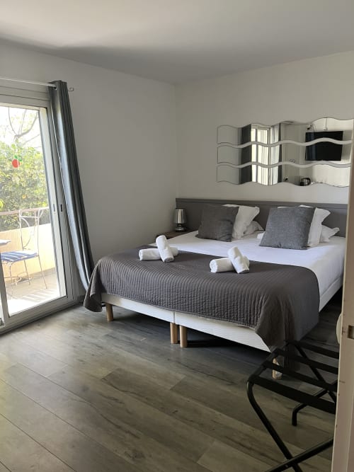 Modern bedroom at Hôtel l'Orangeraie Lavandou with queen bed, garden view balcony, and contemporary furnishings