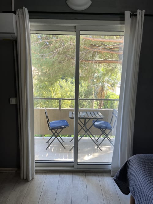 Balcony view from Hôtel l'Orangeraie Lavandou room with garden views, chairs, and lush trees