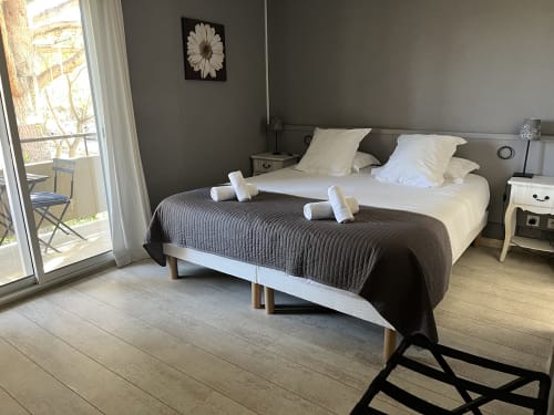 Comfortable twin bed room at Hôtel l'Orangeraie Lavandou with garden view, modern amenities, and balcony access