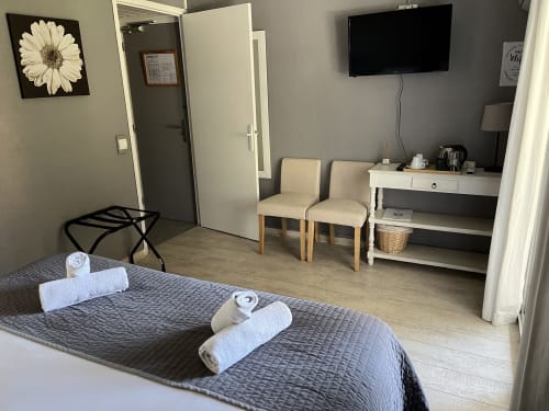 Comfortable hotel room at Hôtel l'Orangeraie Lavandou with queen bed, white towels, seating area, TV, and garden view décor.