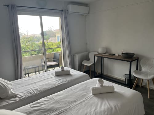 Bright bedroom with two beds, desk, balcony overlooking garden at Hôtel l'Orangeraie Lavandou, Le Lavandou France