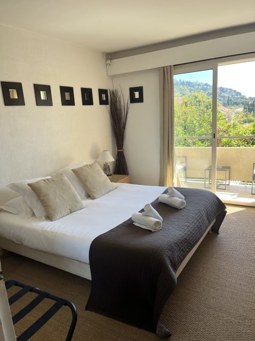 Modern bedroom at Hôtel l'Orangeraie Lavandou with queen bed, garden view balcony, and minimalist decor