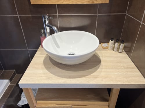 Modern bathroom vanity with white round vessel sink at Hôtel l'Orangeraie Lavandou, featuring wooden countertop and chrome