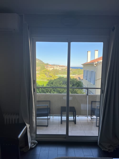 Balcony view from Chambre Côté Jardin at Hôtel l'Orangeraie Lavandou with garden, sea, and Mediterranean architecture