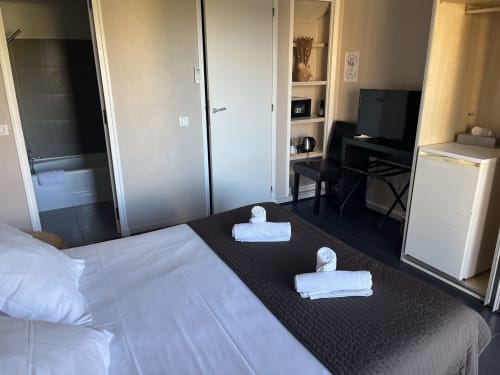 Garden view hotel room at Hôtel l'Orangeraie with bed, TV, bathroom, and amenities in Le Lavandou
