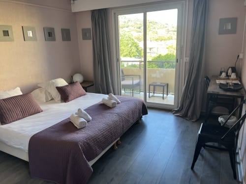 Modern hotel bedroom at Hôtel l'Orangeraie Lavandou with garden view, twin beds, balcony access, and contemporary furnishings