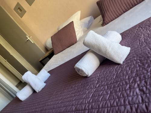 Luxurious hotel bedroom at Hôtel l'Orangeraie Lavandou with fresh white towels arranged on quilted purple bedding