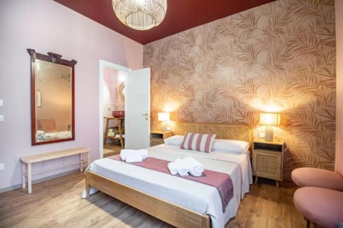 Camera Epimoni Catania bed and breakfast con letto in legno, carta da parati decorativa, specchio e illuminazione calda
