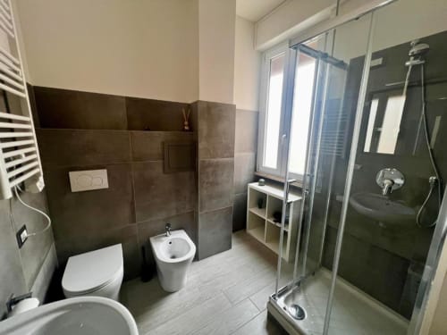 Bagno moderno alla Costabella Guest House con toilette, bidet, box doccia e rivestimento in piastrelle scure