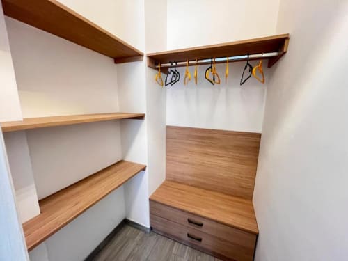 Elegante cabina armadio con ripiani in legno, asta appendiabiti con clips, cassetti di stoccaggio e pareti bianche a Costabella Guest