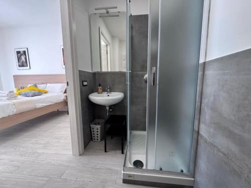 Bagno en-suite moderno con doccia walk-in, lavabo circolare e piastrelle grigio scuro presso Costabella Guest House Roma