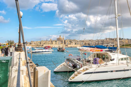 Velieri ormeggiati al porto di Sliema con paesaggio costiero mediterraneo e edifici in calcarenite dorata sullo sfondo