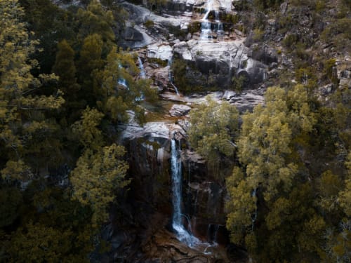 Cachoeira em cascata cercada por floresta de pinheiros na retiro rural Villas Eden em Portugal