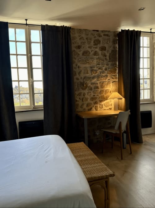 Chambre double du Château de la Borde à Ussel avec murs en pierre, rideaux noirs, bureau et vue sur la campagne