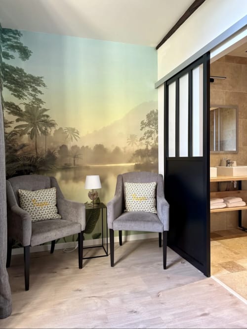 Chambre du Château de la Borde Ussel avec coin détente, deux fauteuils gris et papier peint tropical