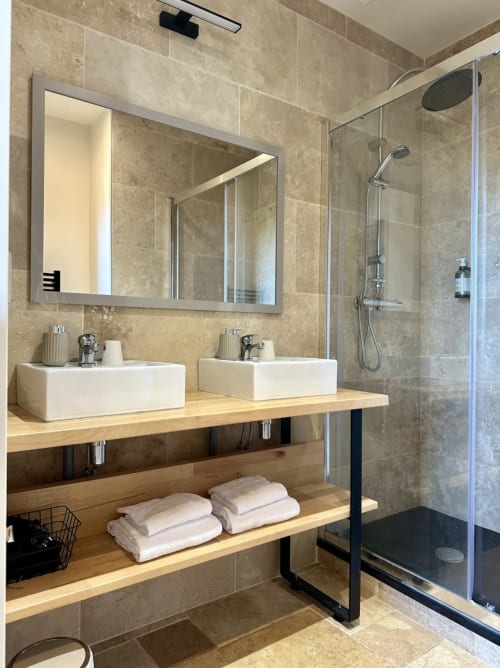 Salle de bains moderne au Château de la Borde avec doubles vasques, grand miroir et douche à l'italienne à Ussel, France