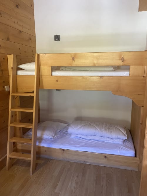 Lit superposé en bois avec literie blanche dans l'appartement La Ferme des Georgières à Notre-Dame-de-Bellecombe