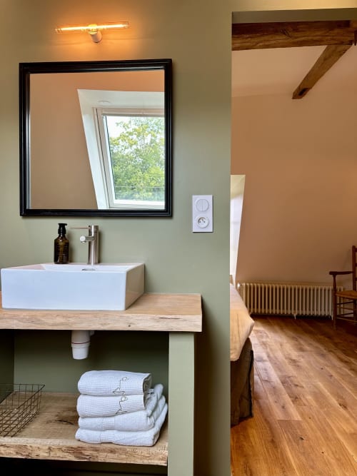 Vasque design moderne et miroir dans la salle de bains du Manoir du Rigouneix, Saint-Angel en France
