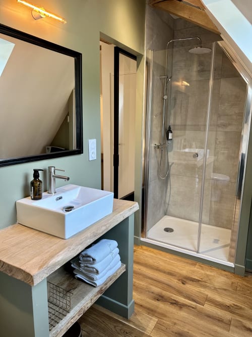 Salle de bain moderne de la Chambre double au Manoir du Rigouneix, Saint-Angel. Lavabo blanc, douche avec paroi vitrée, boiseries.