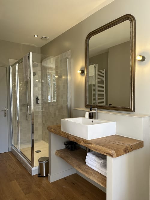 Salle de bains moderne du Manoir du Rigouneix avec vasque design, meuble en bois, miroir orné et douche à l'italienne