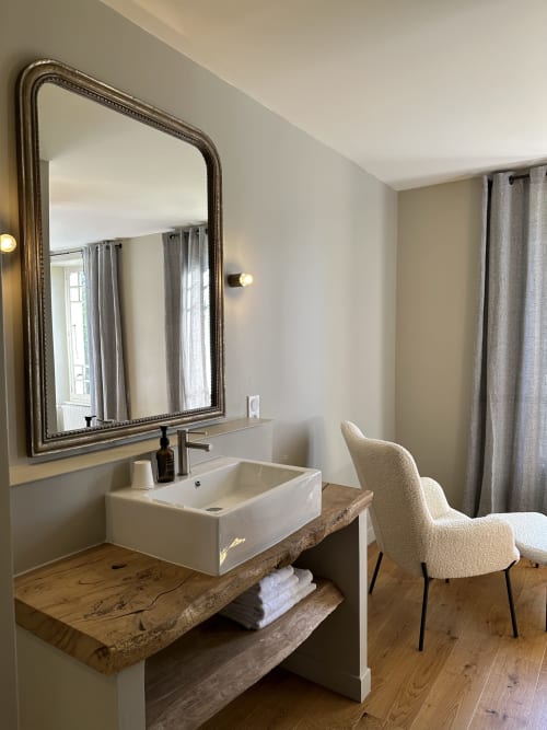 Salle de bain moderne au Manoir du Rigouneix avec vasque, miroir orné, meuble-lavabo bois et chaise à Saint-Angel, France