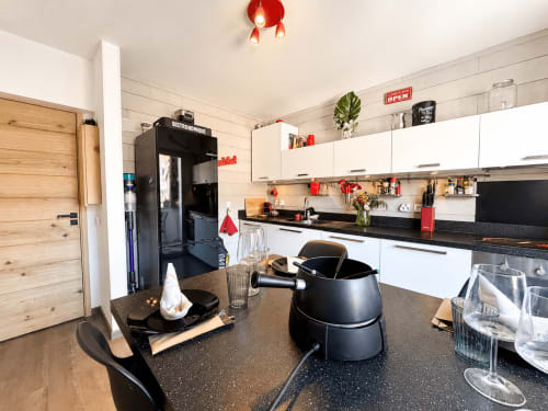 Cuisine moderne de l'appartement 4-étoiles Le 9 Victor Hugo à Aix-les-Bains, avec meubles blancs, plan de travail noir et inox
