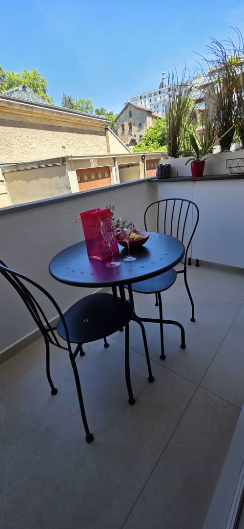 Terrasse sur le toit du 9 Victor Hugo à Aix-les-Bains avec table bleue, chaises noires, lanterne rouge et vue sur la ville