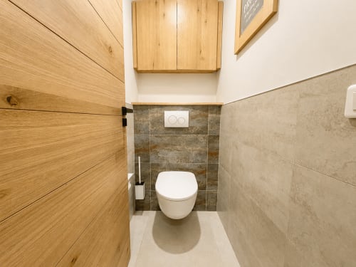 Salle de bain moderne de l'appartement Le 9 Victor Hugo à Aix-les-Bains avec toilettes suspendues et murs carrelés