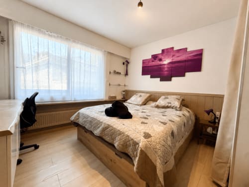 Chambre moderne de l'appartement Le 9 Victor Hugo à Aix-les-Bains avec lit en bois, grande fenêtre et œuvre d'art coucher de soleil violet