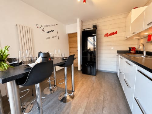 Cuisine moderne et coin repas de l'appartement Le 9 Victor Hugo à Aix-les-Bains avec bar noir et places assises
