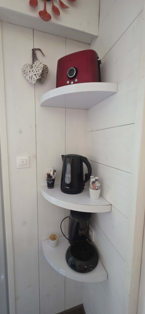 Coin cuisine avec étagères dans l'appartement Le 9 Victor Hugo : grille-pain rouge, bouilloire électrique, cafetière noire