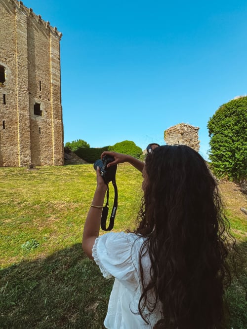 Woman photographing medieval castle ruins at You & Me Glamping in Moncontour, France