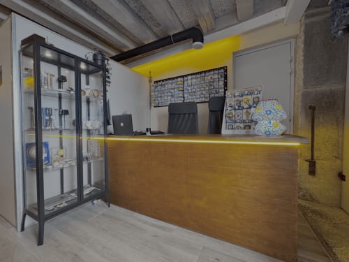Hostel reception desk at Albergue Santiago de Caminha with yellow accent wall, wooden counter, and display shelves in