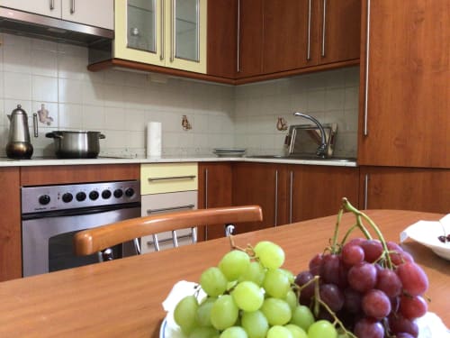 Cocina moderna con muebles de madera, electrodomésticos de acero inoxidable y uvas frescas en la mesa del comedor de la cabaña Houses by Pilar