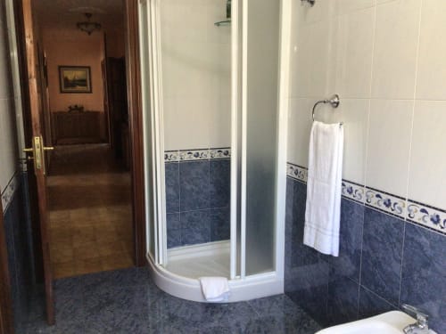 Baño moderno en la casa rural Houses by Pilar en Soutomaior con ducha de esquina, azulejos azul oscuro y toallero blanco