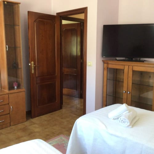 Amplio dormitorio en casita de Houses by Pilar con muebles de madera, sábanas blancas, TV de pantalla plana y vistas a las montañas