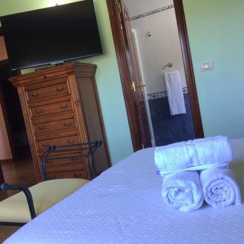 Dormitorio de cabaña en Houses by Pilar, Soutomaior con toallas enrolladas en la cama, cómoda de madera, televisor y baño privado