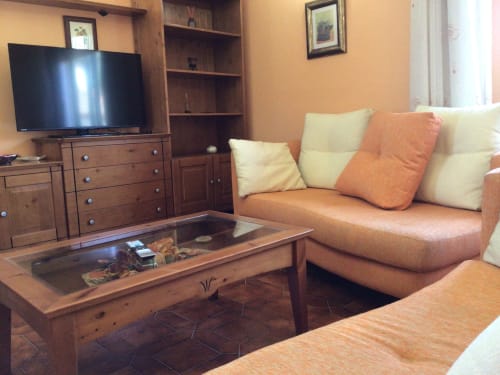 Acogedora sala de estar en Houses by Pilar con sofá naranja, muebles de madera, TV y vistas a la montaña en Soutomaior